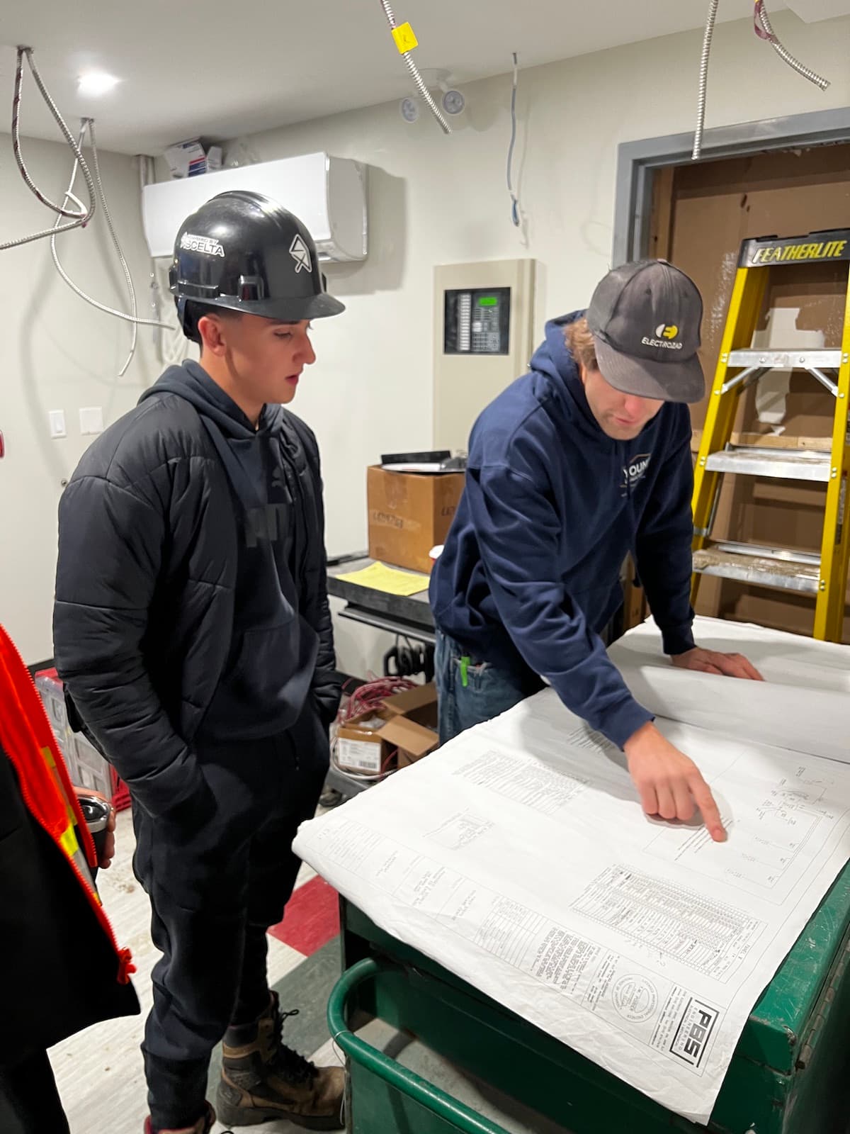 Construction students reviewing electrical drawings on site with a Scelta-supervised crew